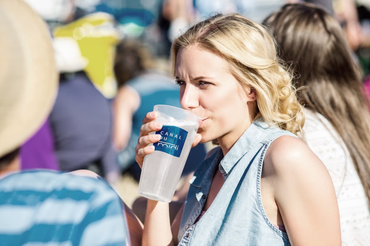 Une femme avec un verre avec le logo Canal du Midi